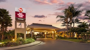 Ein Hotel Eingang mit einem Schild, auf dem „Best Western Plus South Coast“ steht, und einem überdachten Parkbereich.
