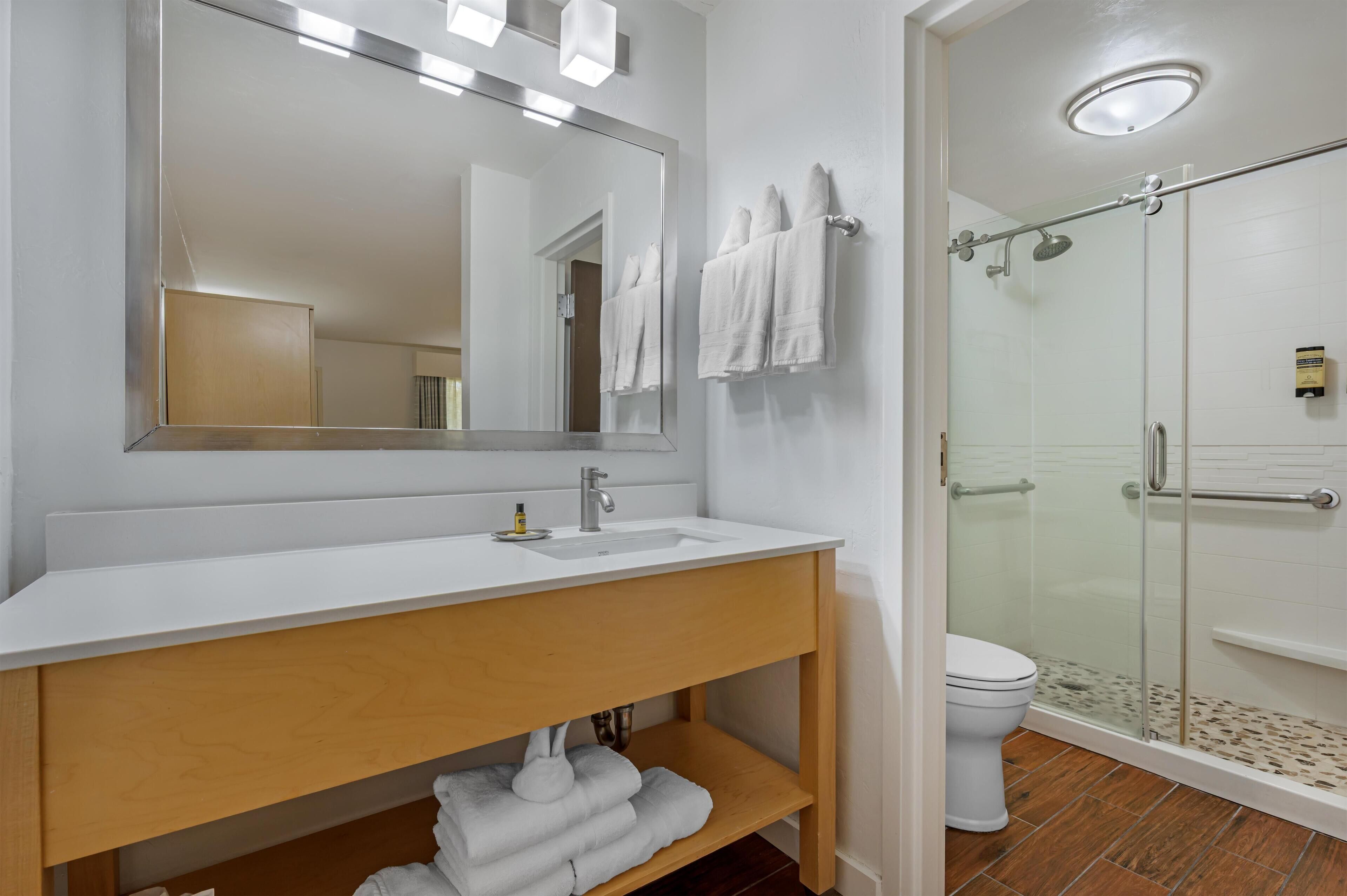 Un baño con lavamanos blanco, espejo y cabina de ducha de vidrio.