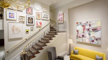 A staircase with a modern design, a yellow sofa, and various framed artworks on the walls.