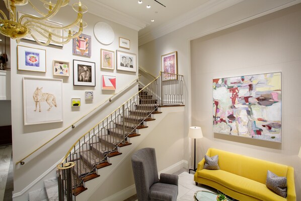 A staircase with a modern design, a yellow sofa, and various framed artworks on the walls.