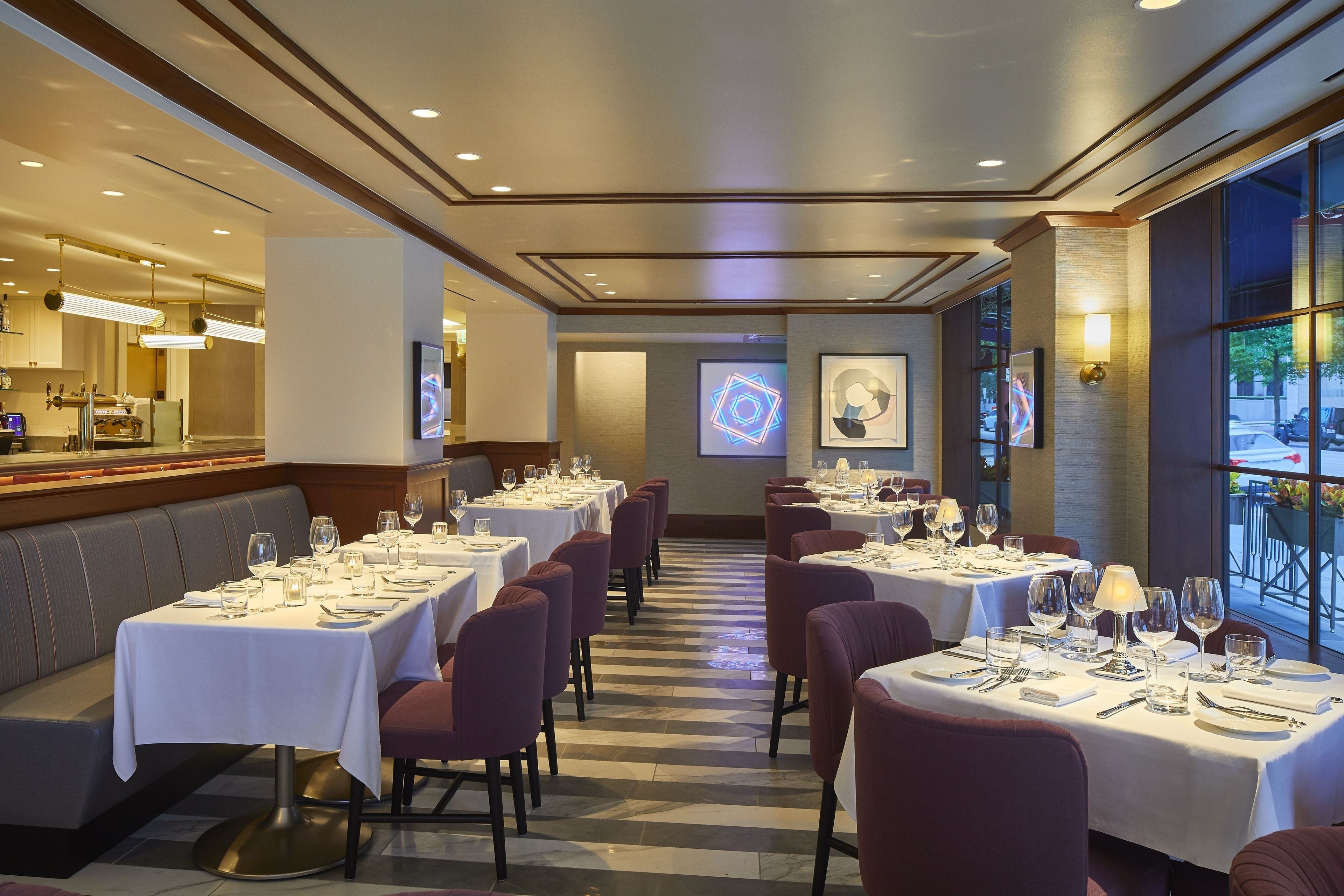 Un restaurant avec des tables dressées pour le service, un coin bar et un écran de projection fixé au mur.