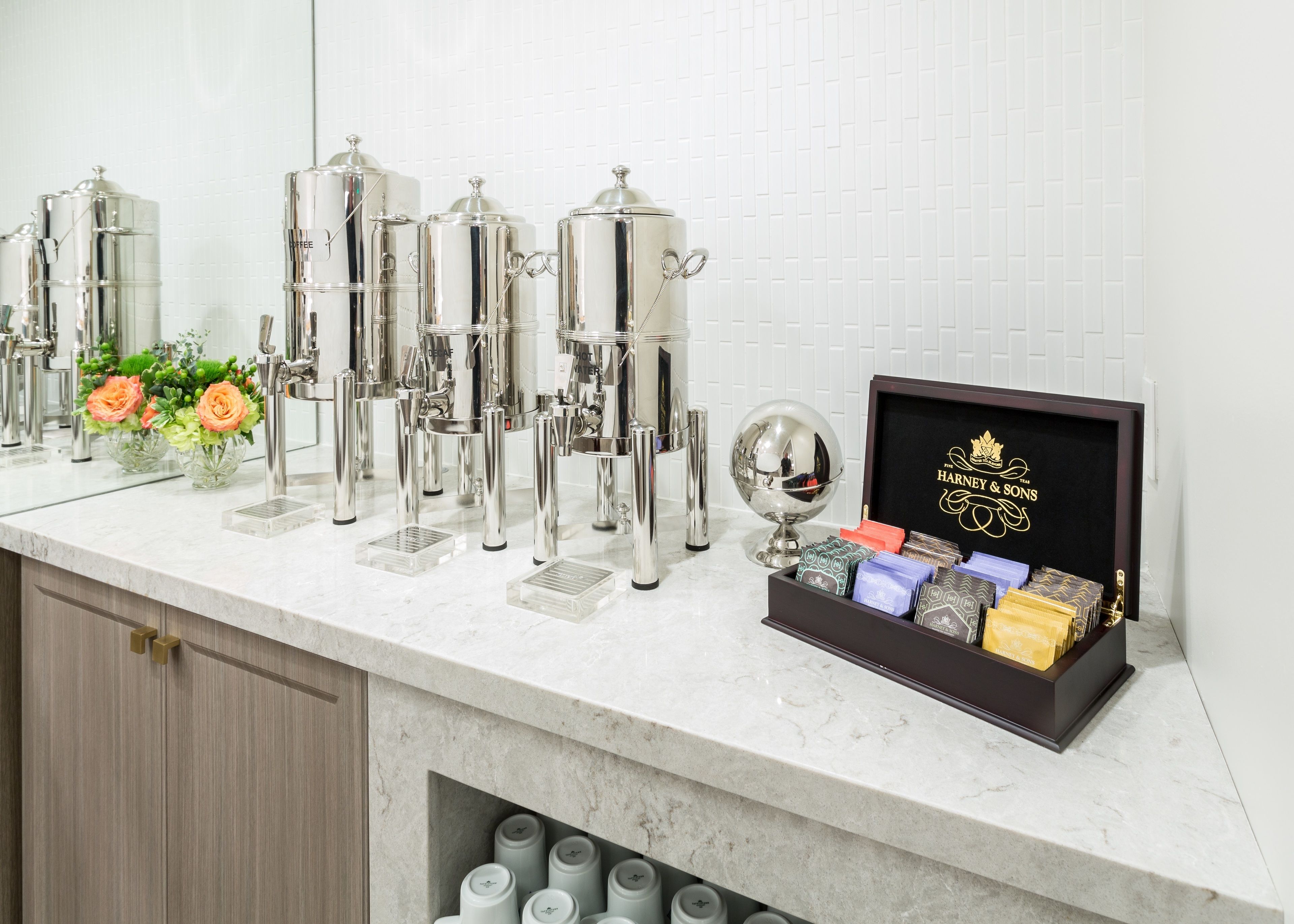 A kitchen counter with stainless steel appliances, a flower arrangement, and a display case with branded items.