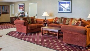 A hotel lobby with a red patterned carpet, two sofas with patterned cushions, a coffee table, and framed pictures on the walls. - Blue Way Inn Eagan Extended Stay Minneapolis Airport Eagan North MN (Eagan)
