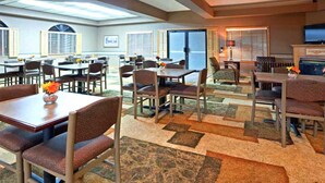 A spacious dining area with multiple tables and chairs, large windows, and a television. - Blue Way Inn Eagan Extended Stay Minneapolis Airport Eagan North MN (Eagan)
