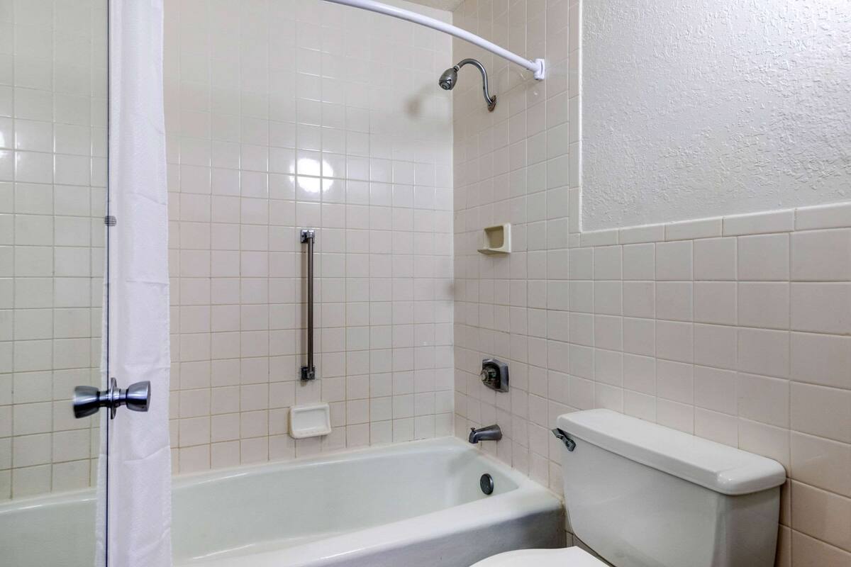 A bathroom with a bathtub, toilet, and a shower area.
