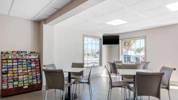 Un espace repas avec des tables et des chaises, un distributeur automatique et un téléviseur fixé au mur.