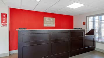 A reception desk with a red wall and a sign that reads "EconoLodge CHOICE".