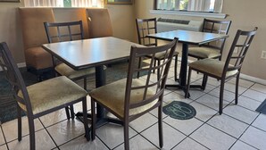 Un comedor con una mesa, sillas, un banco y una ventana con persianas.