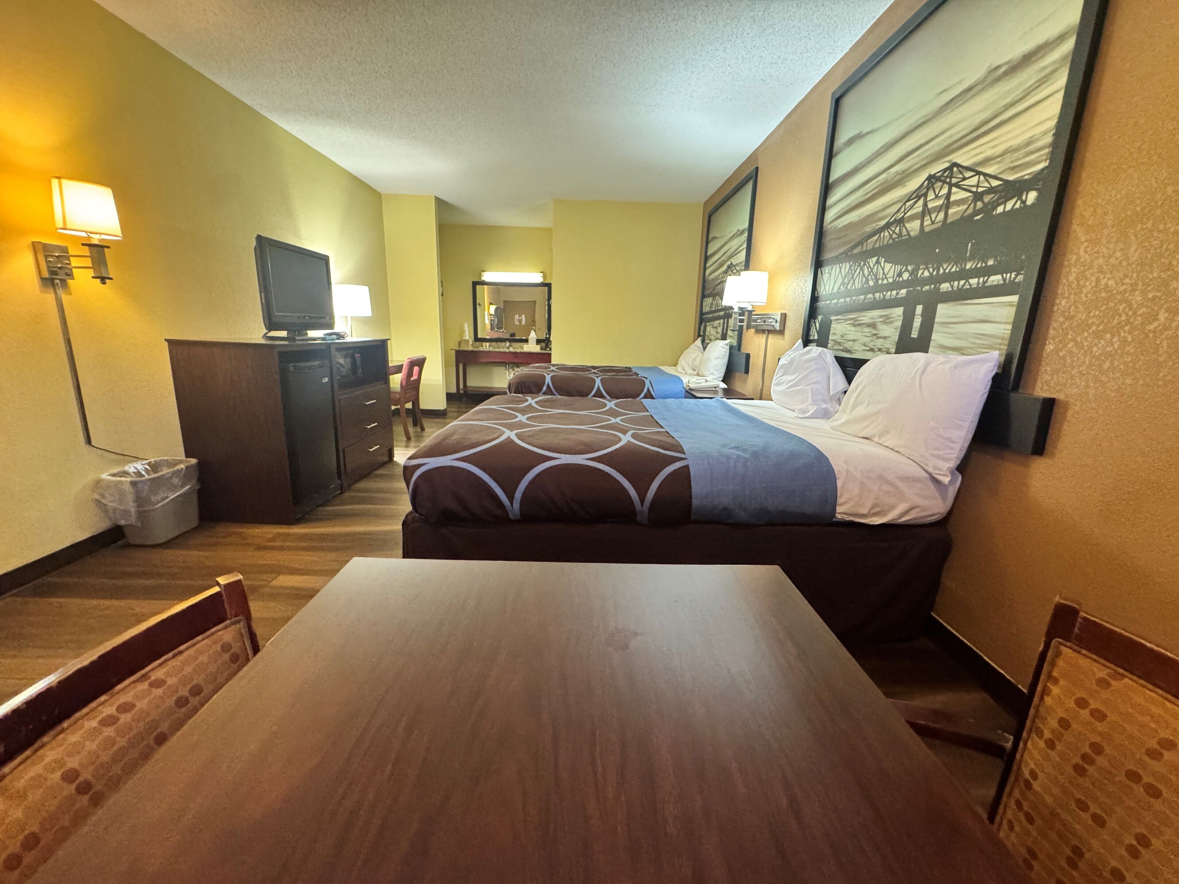 Een hotelkamer met een bed, een bureau, een stoel, een televisie en een groot raam met uitzicht op een brug.