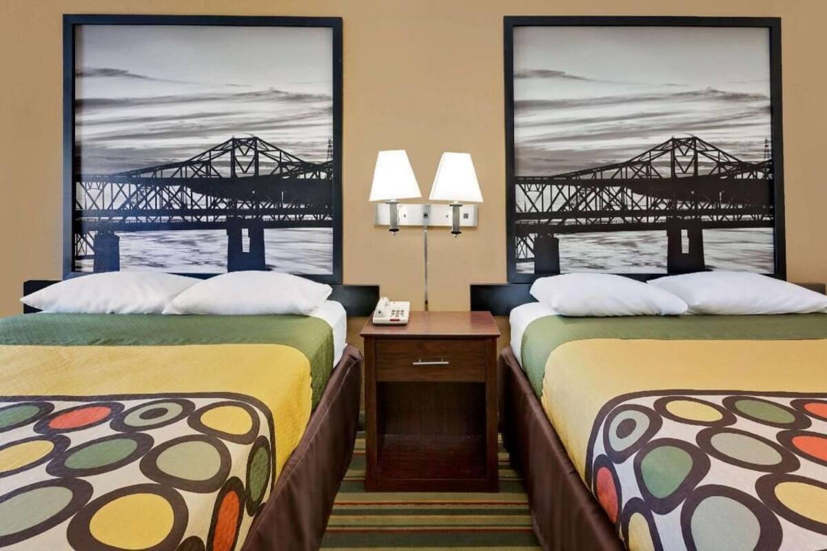 Una habitación de hotel con dos camas, una mesita de noche y dos lámparas de pared.