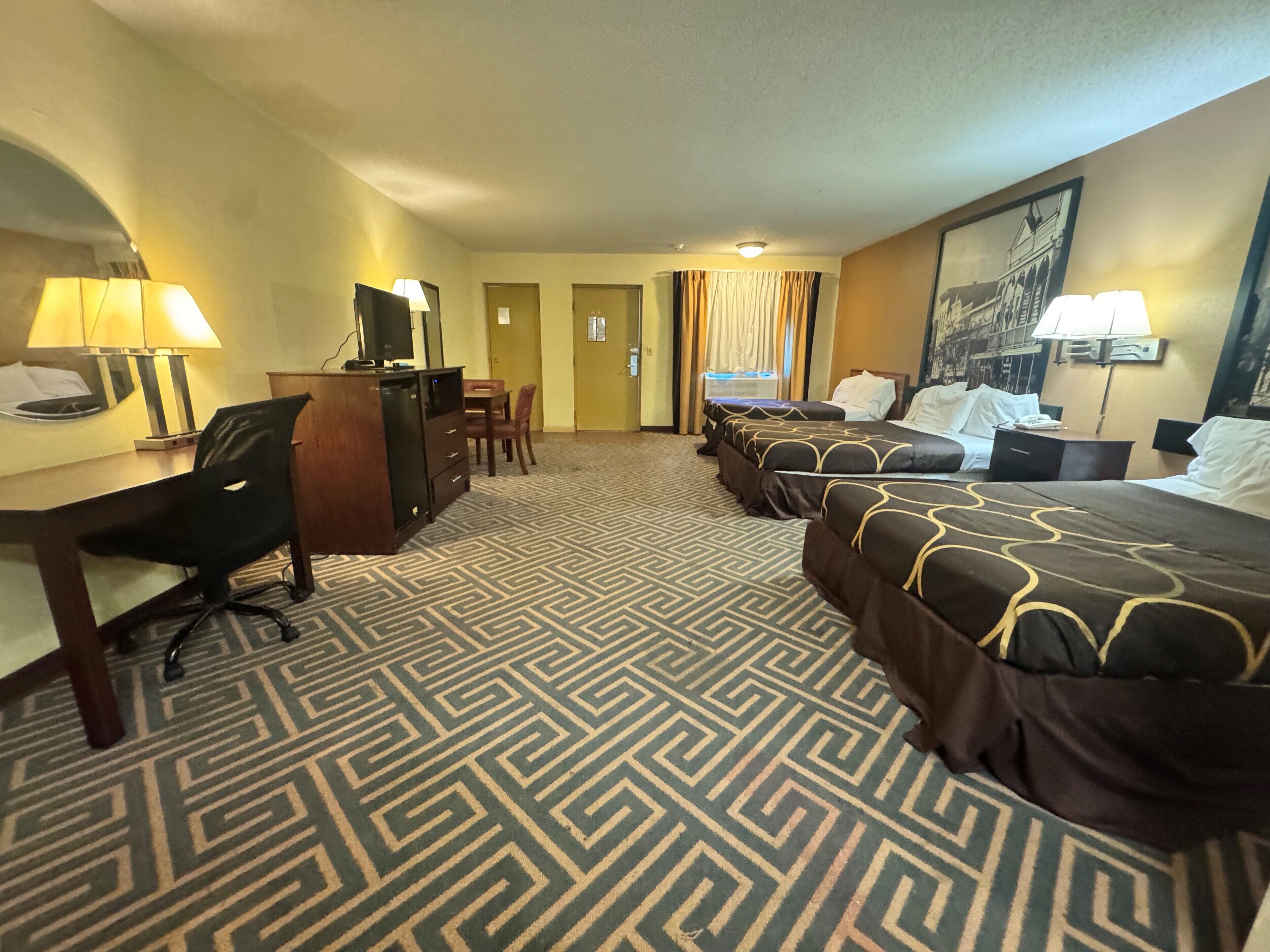 A hotel room with two beds, a desk with a chair, a TV, and a minibar.