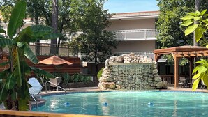 A pool with a waterfall feature, surrounded by wooden deck and lounge chairs. - Best Western Inn of the Ozarks (Eureka Springs)