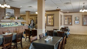 A restaurant with multiple tables and chairs, a buffet area, and a counter with food displays. - Best Western Inn of the Ozarks (Eureka Springs)