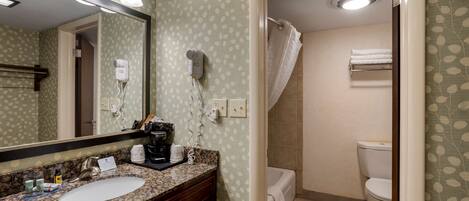 A bathroom with a sink, mirror, hairdryer, and towel rack.