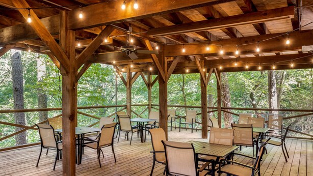 An outdoor wooden deck with tables and chairs, surrounded by trees. - Best Western Inn of the Ozarks (Eureka Springs)