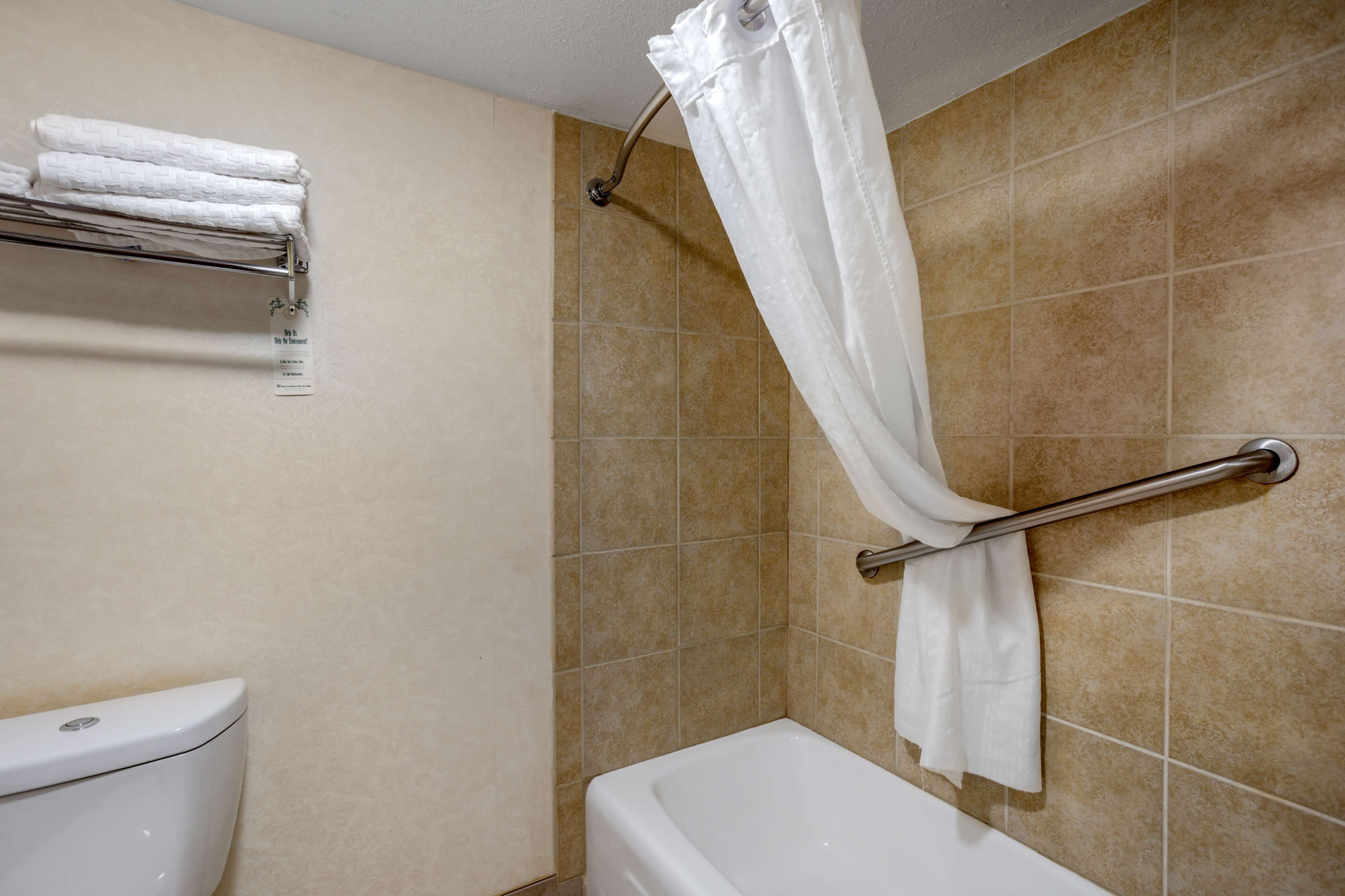 Un baño con inodoro, ducha con cortina y toallero con toallas dobladas.