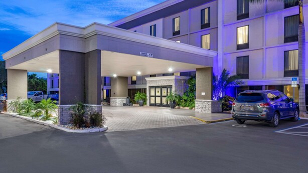 A hotel entrance with a covered parking area, a sign indicating handicap accessibility, and a vehicle parked in the lot. - Comfort Inn & Suites St. Pete - Clearwater International Airport (Clearwater)