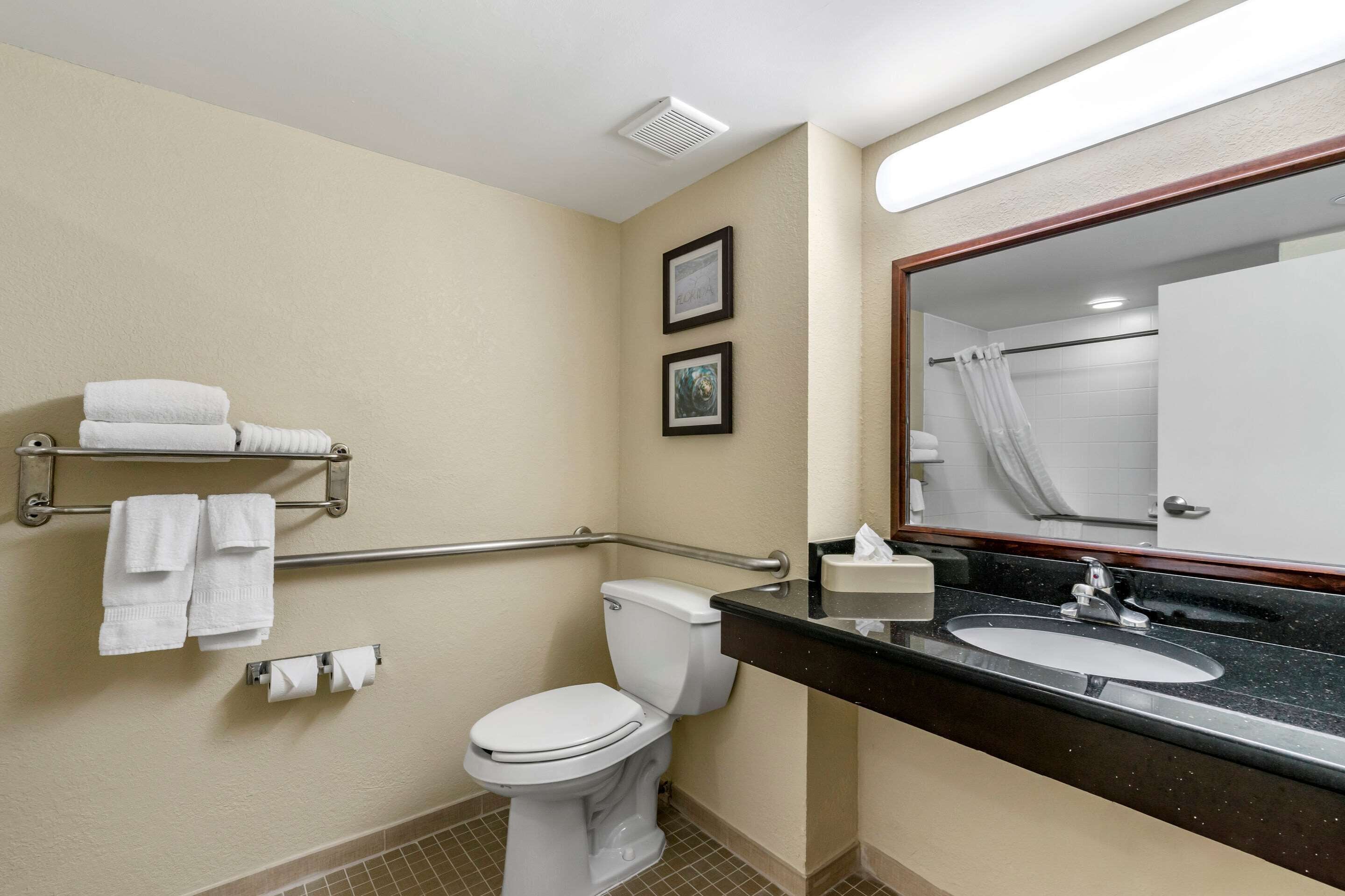 Une salle de bain d’hôtel équipée de toilettes, d’un lavabo et de barres d’appui.