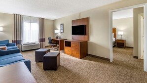 A hotel room with a flat-screen TV, a desk, a chair, a sofa, a coffee table, and a lamp. - Comfort Inn & Suites St. Pete - Clearwater International Airport (Clearwater)