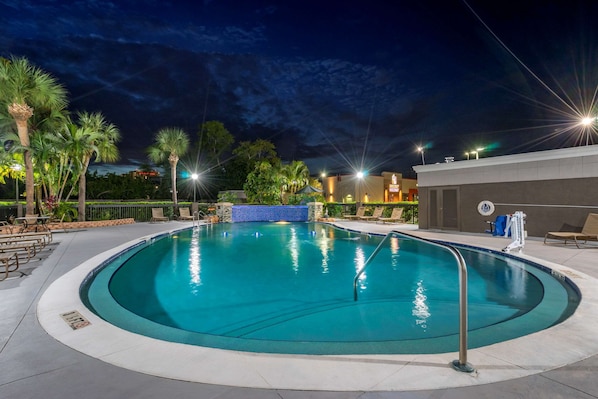 Una piscina al aire libre, sombrillas, sillones reclinables de piscina