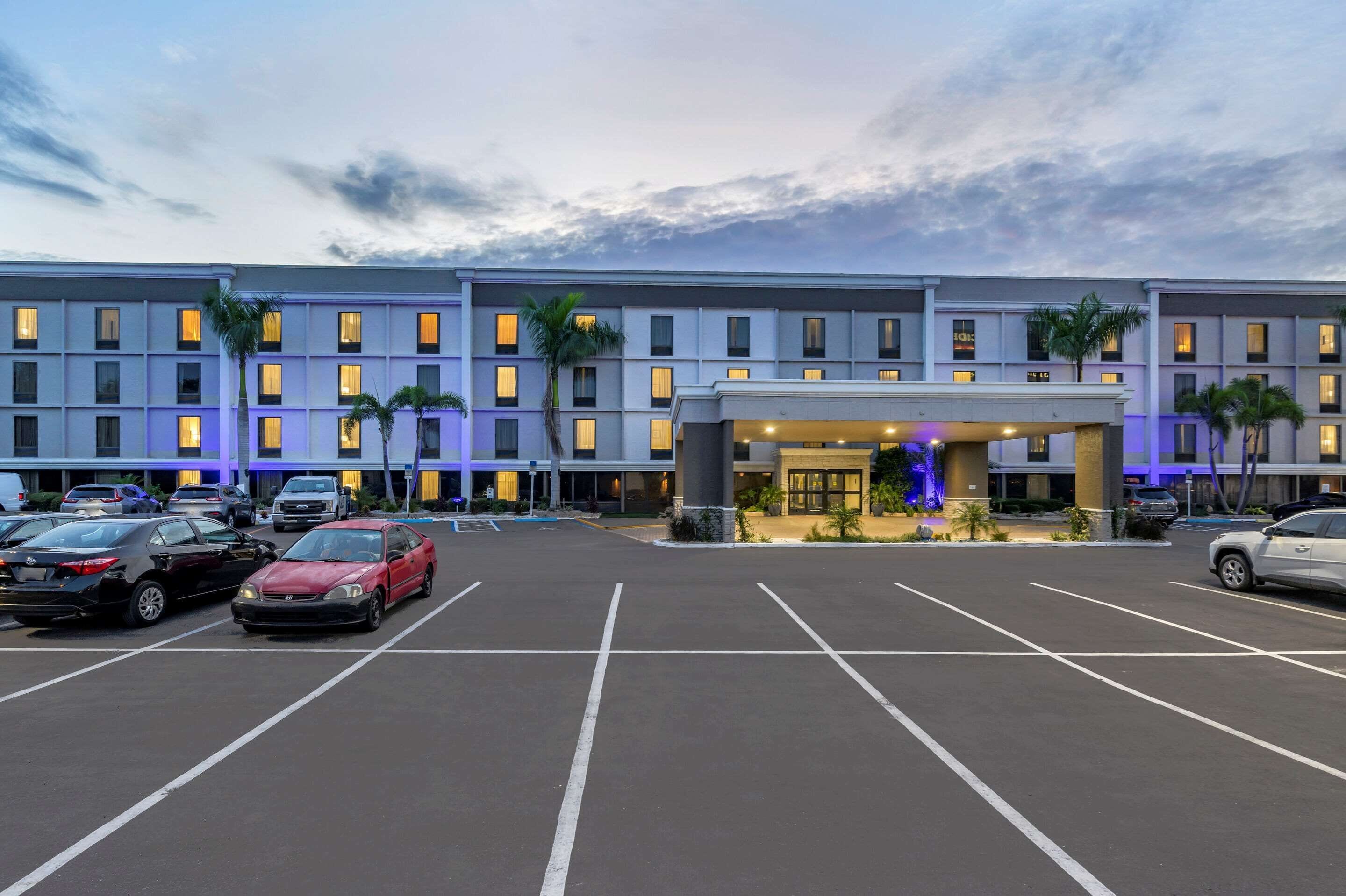 Un hotel de varios pisos con un estacionamiento al frente.