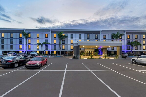 Un hotel de varios pisos con un estacionamiento al frente.
