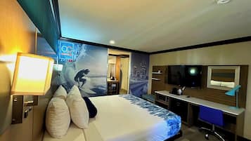 Habitación de hotel con cama, escritorio, televisor y un mural con vista urbana.