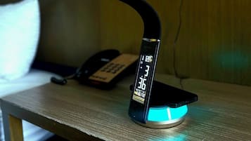 A desk with a desk lamp, a phone, and a digital clock displaying the time.