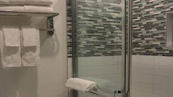 Ein modernes Badezimmer mit einer Duschkabine, einer Toilette und einem Handtuchhalter mit gefalteten Handtüchern.