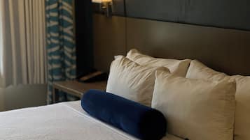 Un lit bien fait, avec des oreillers blancs et bleus, une tête de lit en bois et une lampe de chevet.
