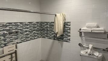 Une salle de bain moderne avec une zone de douche carrelée, une paroi de douche en verre et des toilettes dotées d’un porte-serviettes.