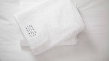 A folded white towel with a label on a white bedspread.