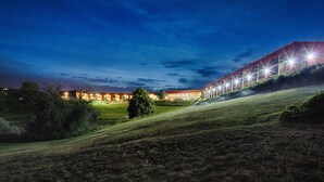 A modern building with multiple illuminated windows and a sloped roof, surrounded by a grassy area and trees. - Red Lion Hotel Pendleton (Pendleton)