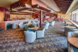 Un hall d’hôtel spacieux, doté de plusieurs espaces salon, d’un bar et d’une moquette à motifs.