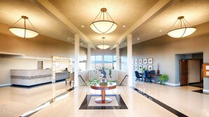 A spacious lobby with a reception desk, a central plant display, and a staircase leading to upper floors. - Red Lion Hotel Pendleton (Pendleton)