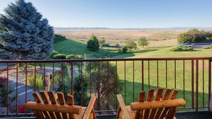 A balcony with two wooden Adirondack chairs overlooking a scenic landscape. - Red Lion Hotel Pendleton (Pendleton)