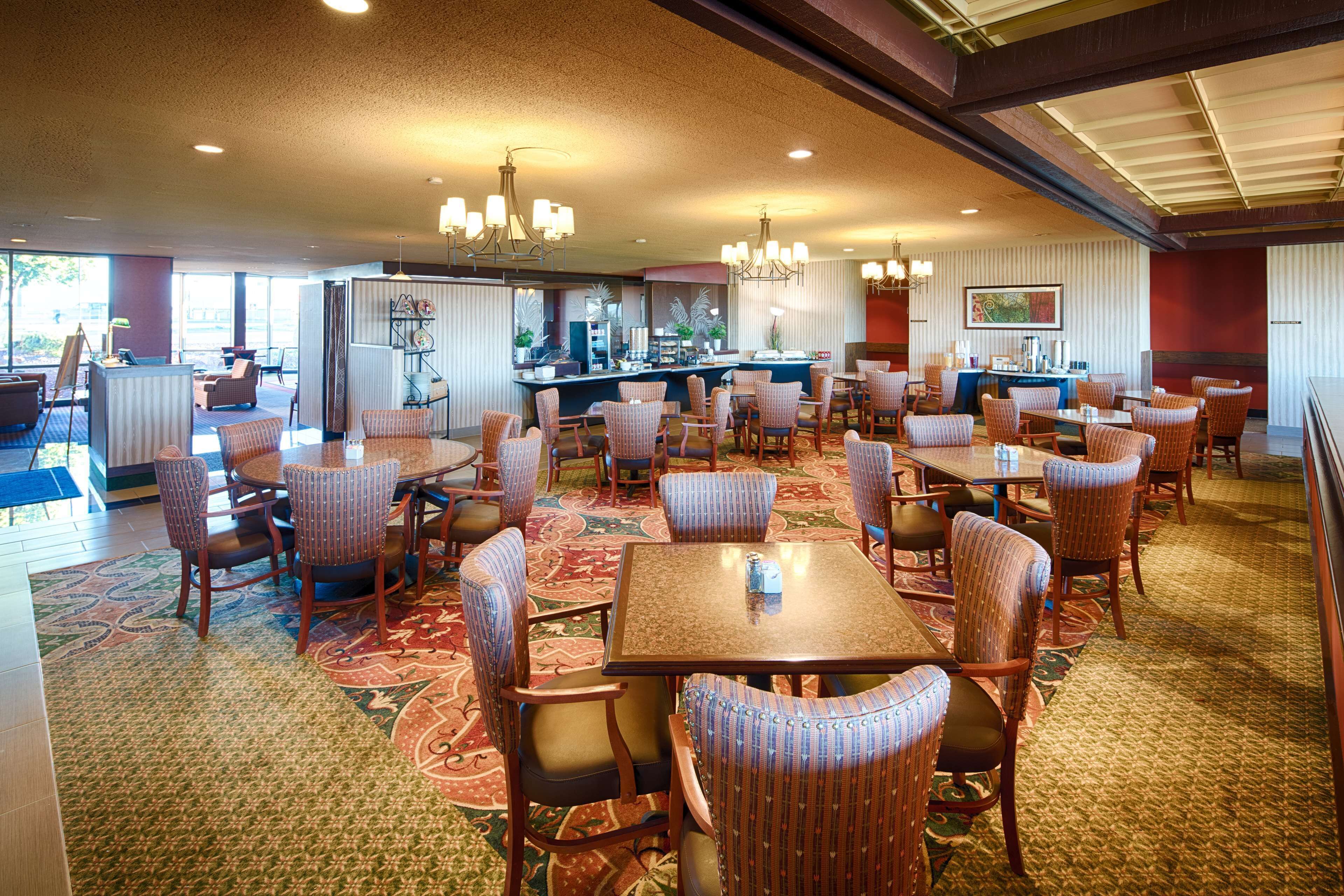 A spacious dining area with multiple tables and chairs, a bar, and a view of the outside.