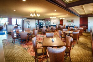 A spacious dining area with multiple tables and chairs, a bar, and a view of the outside.