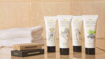 Vier Produkte von Cascadia Soapery und zwei Seifenstücke auf einer Badezimmerablage.