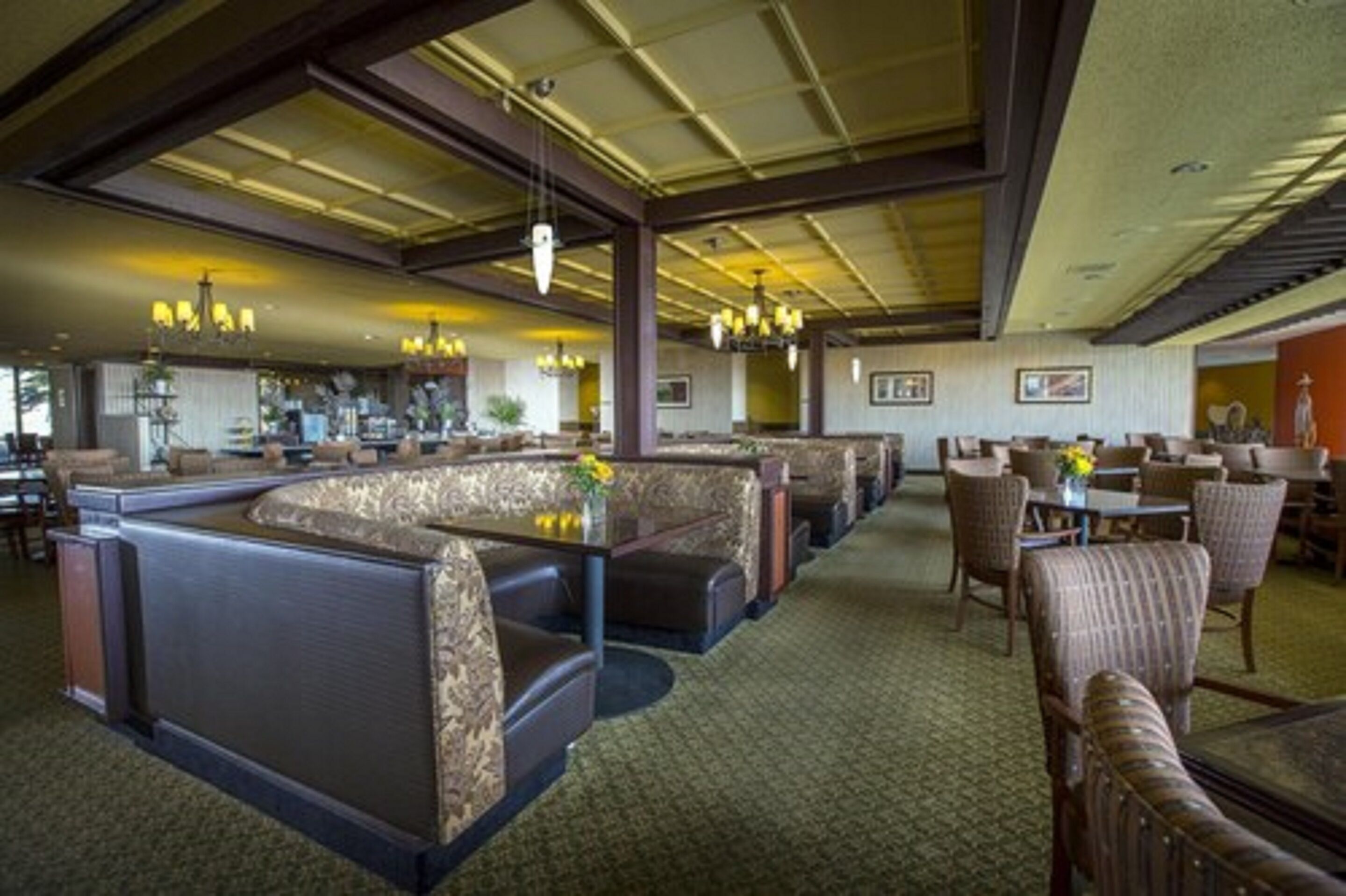 Een ruime lobby met hoge plafonds, meerdere zithoeken en een centrale bar.