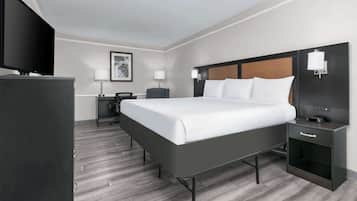 A modern hotel room with a large bed, a flat-screen TV, a desk, and a chair.