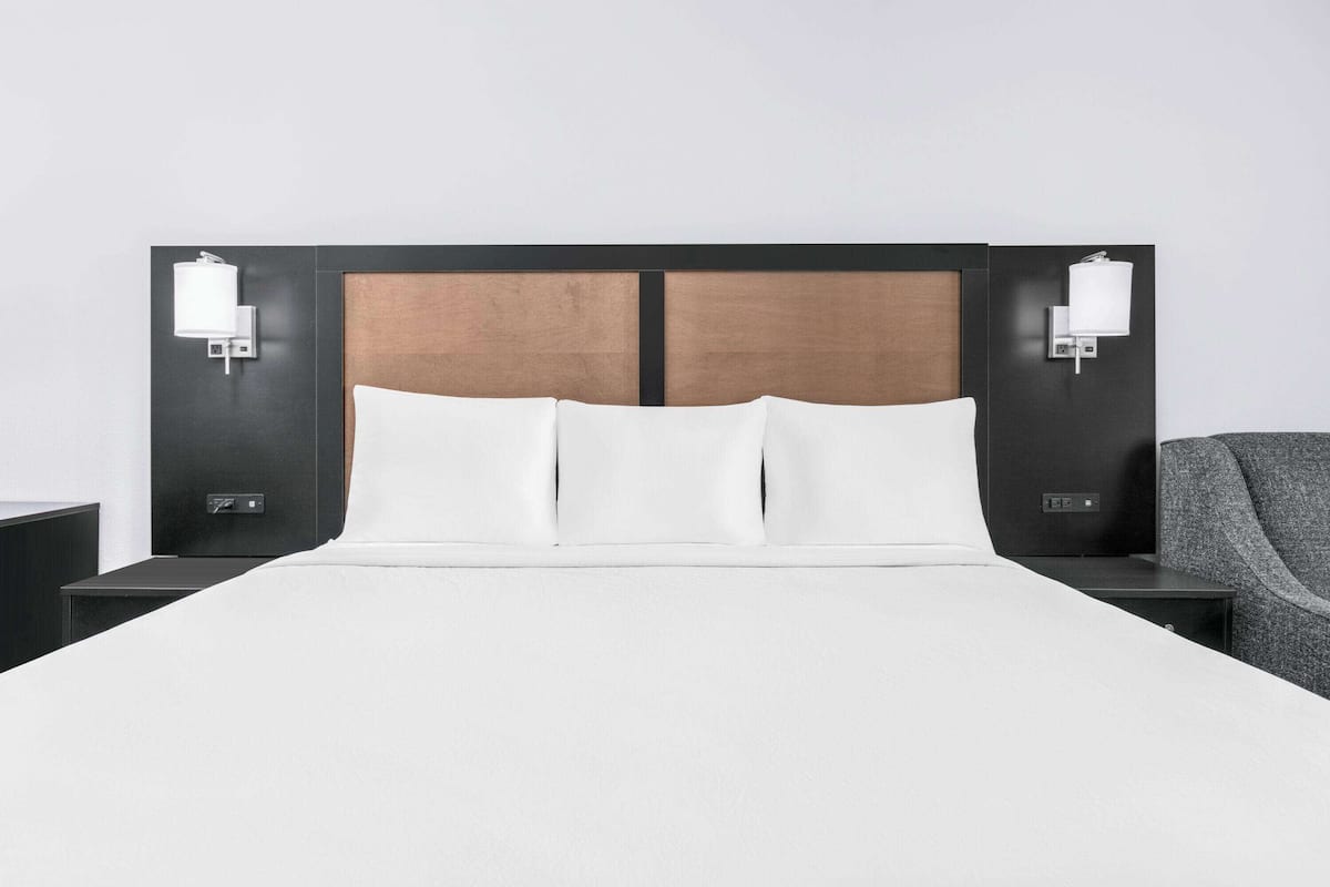 A modern hotel room with a large bed, two bedside tables, and a nightstand.