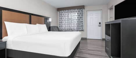 Una habitación de hotel moderna con una cama grande, televisor, escritorio y armario.