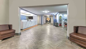 Un hall d’entrée spacieux avec un sol décoré d’un motif en chevrons, un comptoir de réception et deux canapés en cuir.