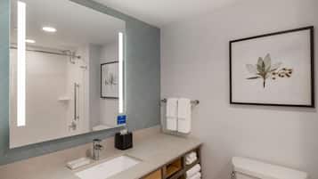 Ein modernes Badezimmer mit großem Spiegel, Waschbecken, Toilette und einem gerahmten Pflanzenbild an der Wand.