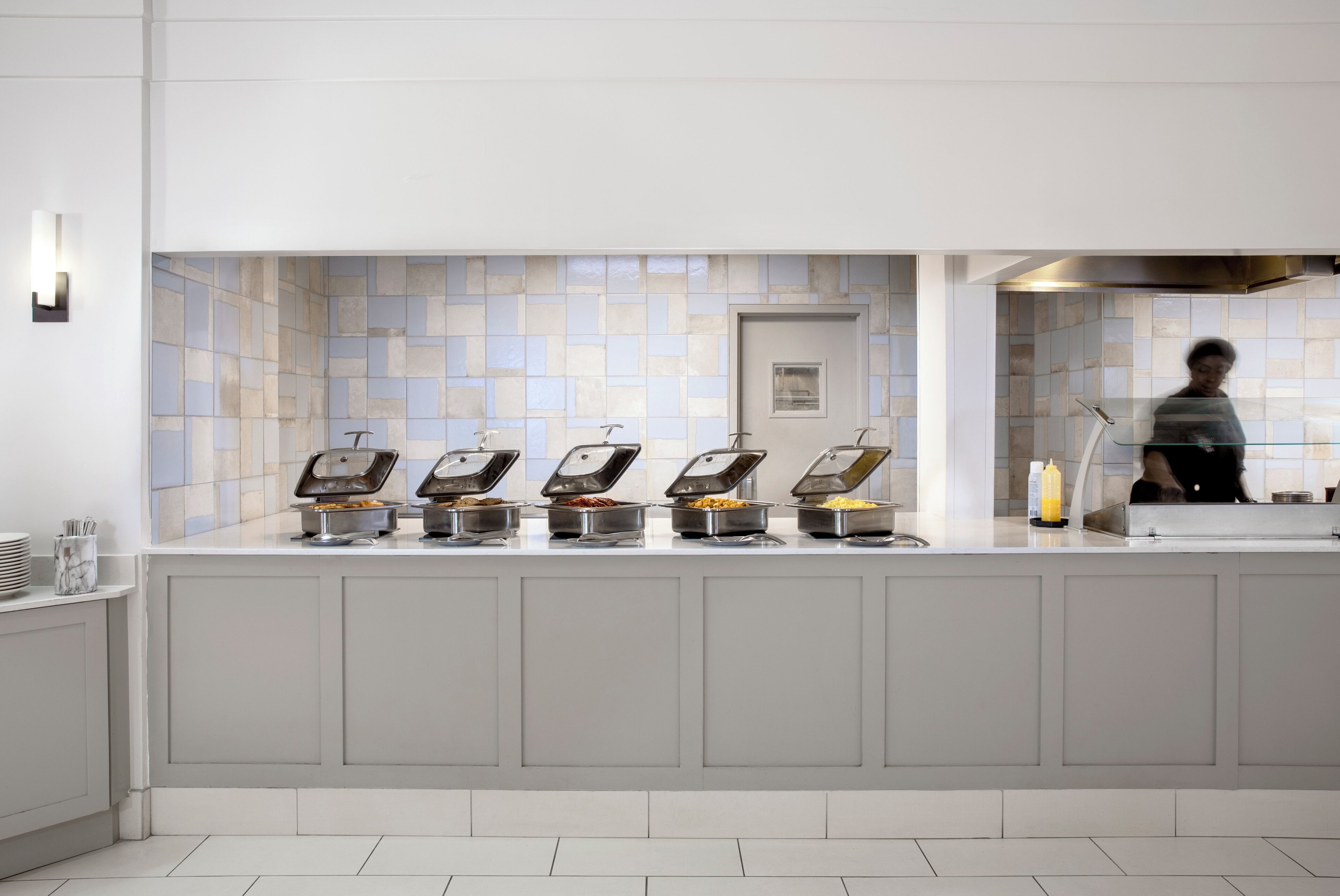 Mostrador de buffet con cinco dispensadores de comida, un lavamanos y un espejo.
