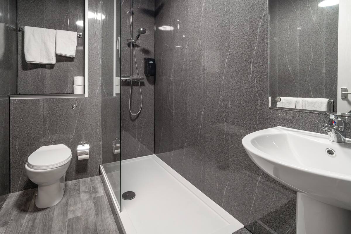 A modern bathroom with a toilet, shower, and sink.