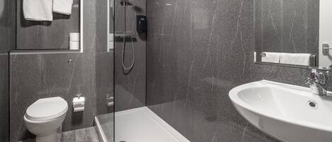 A modern bathroom with a toilet, shower, and sink.