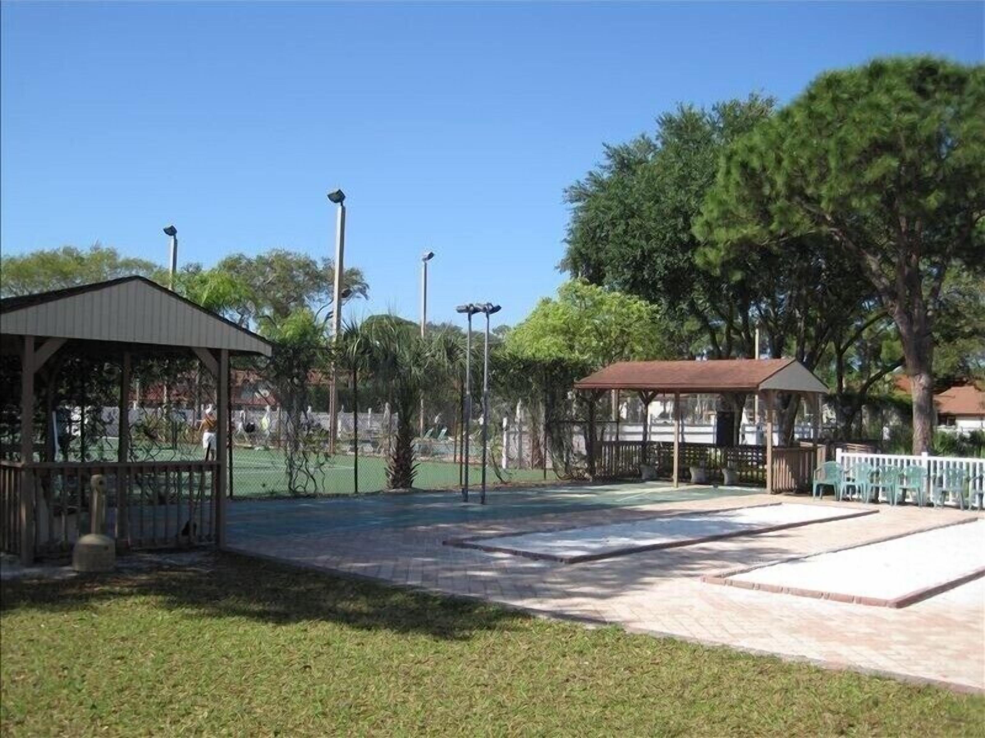 A park with a gazebo, a fenced tennis court, and a picnic area.
