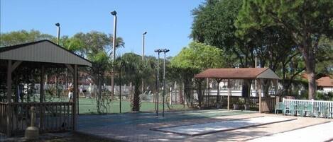 A park with a gazebo, a fenced tennis court, and a picnic area.